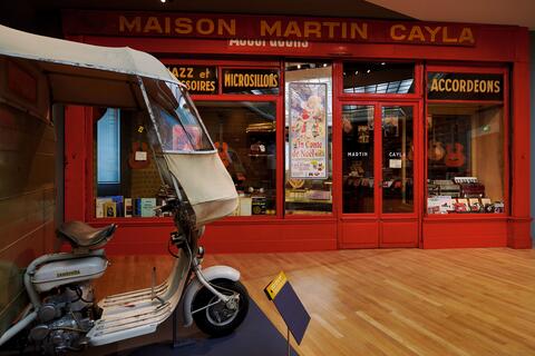 Boutique Cayla  Triporteur Maugein devant la devanture de la Boutique Cayla
